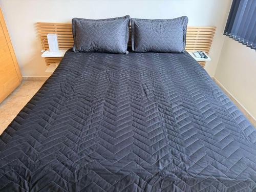 a bed in a bedroom with a gray blanket and pillows at Apartment near Vitosha mountain, self check-in, with underground parking in Sofia