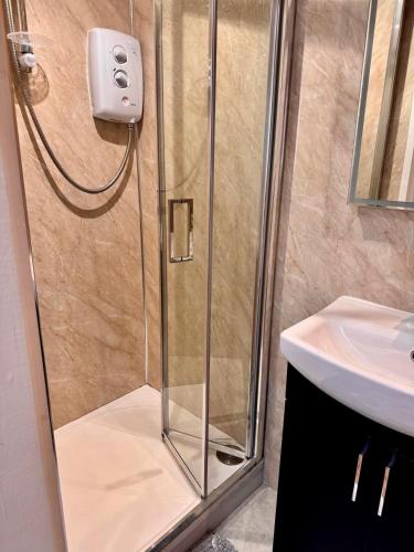 a shower with a glass door next to a sink at Detached one bedroom house near to castle and cathedral in Lincoln