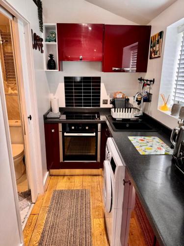 a kitchen with red cabinets and a black counter top at Detached one bedroom house near to castle and cathedral in Lincoln