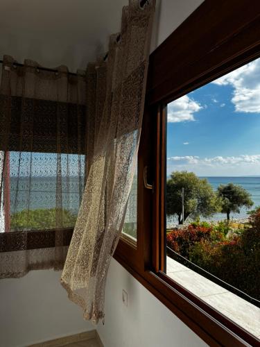 a window with a view of the ocean at Agnanti - Seafront Home with Aegean Sea View in Loutrá Elevtherón