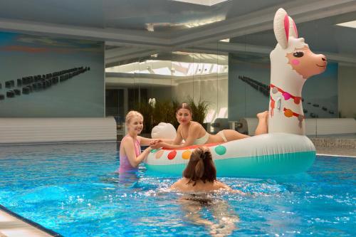 three women in a swimming pool with an inflatable animal at Waterlane Riverside - SPA, Pool, Gym & Parking by Downtown Apartments in Gdańsk
