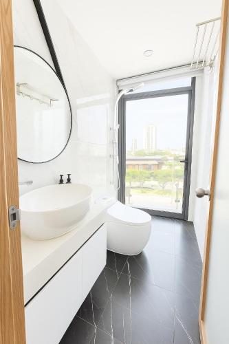 a white bathroom with a sink and a mirror at Louis Luxury Apartment & Hotel in Danang