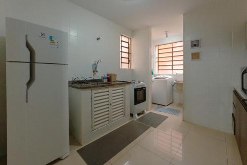 a white kitchen with a refrigerator and a sink at Conforto no Centro de Maringá MC11 in Maringá