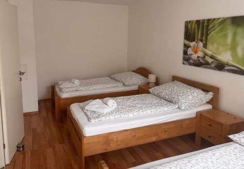 three beds in a room with wooden floors at Apartment im Herzen von Neusiedl am See in Neusiedl am See