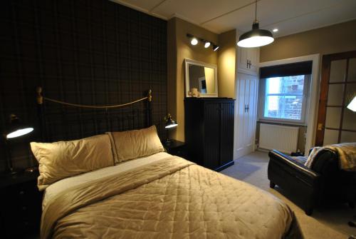 a bedroom with a bed and a chair and a window at 54 On the Rocks- characterful coastal cottage in Anstruther