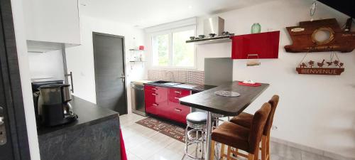 une cuisine avec un comptoir noir et des armoires rouges dans l'établissement L'Echappée Bretonne, à Erdeven