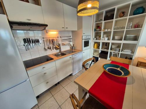 une cuisine avec des armoires blanches et une table en bois dans l'établissement Beau T3 lumineux avec terrasse et parking privé, à Billère