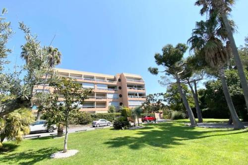 un bâtiment avec des palmiers en face d'un parc dans l'établissement Bright studio with balcony near the harbor, à Saint-Raphaël