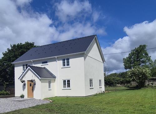 a white house with a black roof at Fig Tree Cottage in North Cornelly