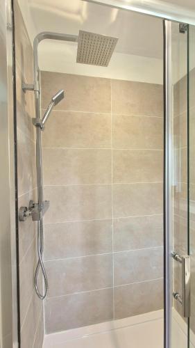 a shower with a glass door in a bathroom at Fig Tree Cottage in North Cornelly