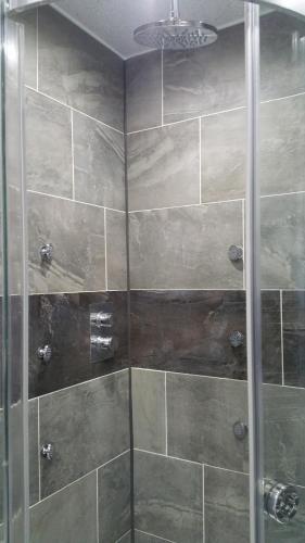 a shower with a glass door in a bathroom at Canalside Beautiful Stone Townhouse in Stone