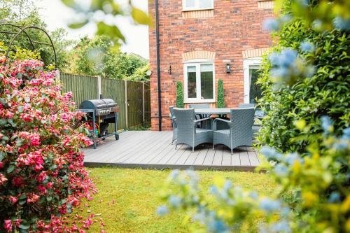 a patio with two chairs and a grill in a yard at Canalside Beautiful Stone Townhouse in Stone