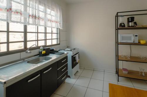 a kitchen with a sink and a stove at Apartamento Econômico - AL09 in Maringá