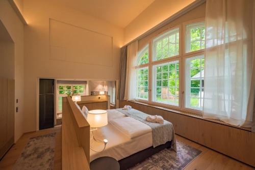 a bedroom with a bed and two windows at Gutshotel Menterschwaige in Munich