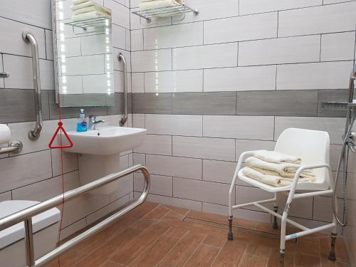 ein Badezimmer mit einem Waschbecken, einem Stuhl und einem Spiegel in der Unterkunft Beech Cottage in Boston