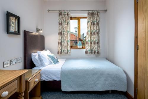 ein kleines Schlafzimmer mit einem Bett und einem Fenster in der Unterkunft Beech Cottage in Boston