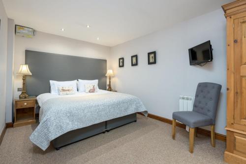 ein Schlafzimmer mit einem Bett und einem Stuhl und einem Fernseher in der Unterkunft Ash Cottage in Boston