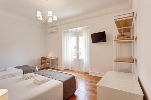 a white room with two beds and a television at Home Out Rooms & Apartments in Lisbon