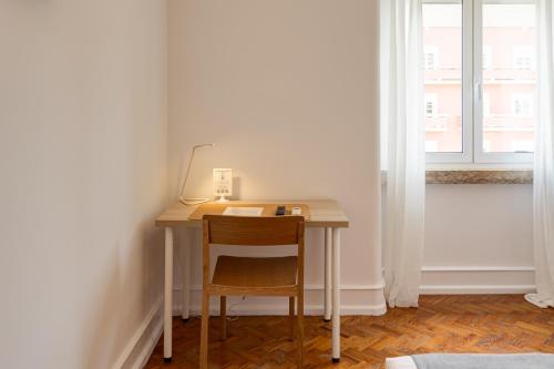 a desk with a chair in a room with a window at Home Out Rooms & Apartments in Lisbon