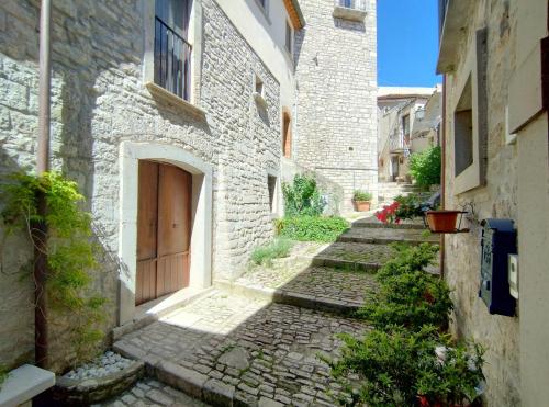 an alley with stone buildings and a wooden door at LA ROCCIA DI VICIDOMINI - Affittacamere in San Marco dei Cavoti