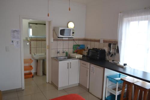 a small kitchen with a sink and a microwave at Driftsands Sea View Flats in Uvongo Beach