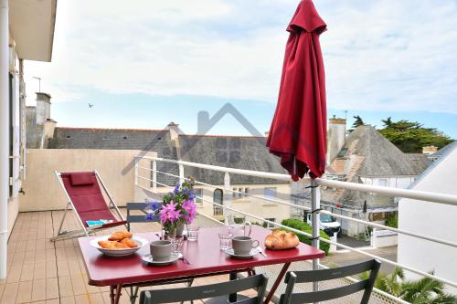 - un balcon avec une table et un parasol rouge dans l'établissement LocaLise - D80 - La villa Blanche - Côté plage - 2ème étage - Wifi inclus - Draps inclus - Animaux bienvenus, au Guilvinec