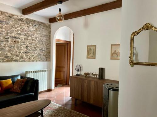 a living room with a couch and a stone wall at Casa Bel Tempo in Pieve di Teco