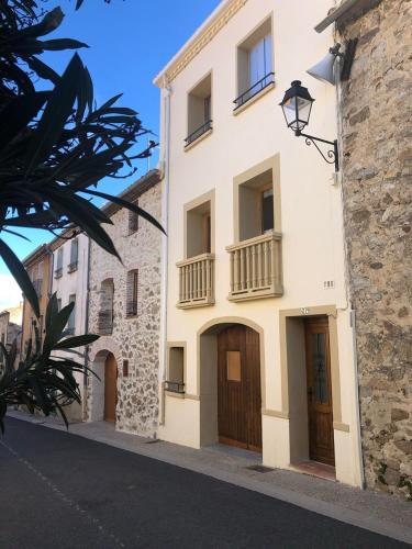 - un bâtiment blanc avec des portes en bois dans une rue dans l'établissement Pure Canigou House An Authentic and Charming Town house with 3 bedrooms, à Montalba-le-Château