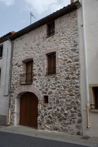 - un vieux bâtiment en pierre avec une porte et des fenêtres dans l'établissement Pure Canigou House An Authentic and Charming Town house with 3 bedrooms, à Montalba-le-Château