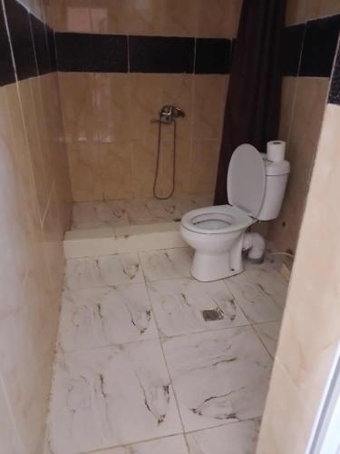 a bathroom with a toilet and a tiled floor at New Wave1 in Grigoleti