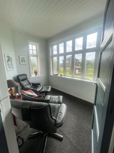 a living room with two chairs and windows at Dubbelrum Værøy in Værøy