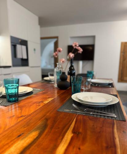 a wooden table with plates and glasses on it at Moderne helle Ferienwohnung 1-6 Pers - Chasa32 in Guarda in Guarda