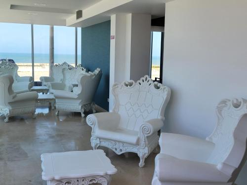 a group of white chairs and tables in a room with the ocean at Hotel Mar e Sol & Spa in São Pedro de Moel