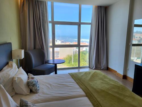 a hotel room with a bed and a large window at Hotel Mar e Sol & Spa in São Pedro de Moel