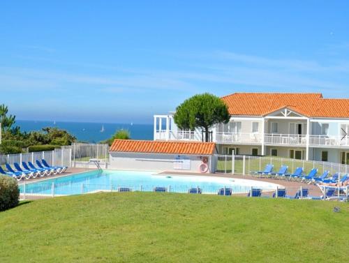 une maison avec une piscine entourée de chaises et l'océan dans l'établissement T2 Cosy, Piscine, Parking et Résidence front mer, à Les Sables-dʼOlonne