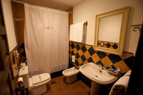 a bathroom with a sink and a toilet and a mirror at Palacio las Manillas in Sabiote