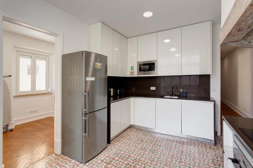 a kitchen with white cabinets and a stainless steel refrigerator at Home Out Rooms & Apartments in Lisbon