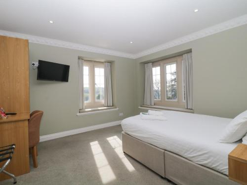 a bedroom with a bed and a tv and windows at Harcombe Heights at Harcombe House in Newton Abbot