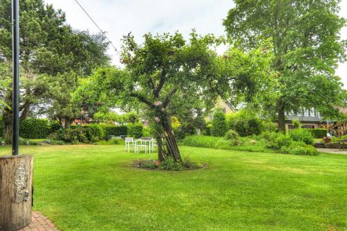 a tree in the middle of a lawn with a table at Göckes Haus Und Garten Lavendelbeet in Wettringen