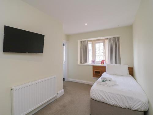 a bedroom with a bed and a flat screen tv at Harcombe House Rooms - First Floor Single in Newton Abbot
