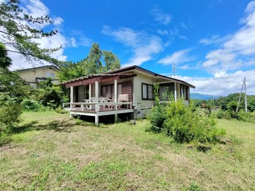 a small house with a porch on a field at Kitakaruizawa Morino Bessou NO7 in Kita-karuizawa