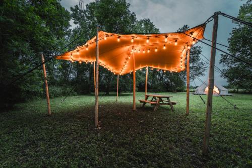 une tente orange avec des lumières et une table de pique-nique dans l'établissement Campement au reve - Genouilleux, à Genouilleux
