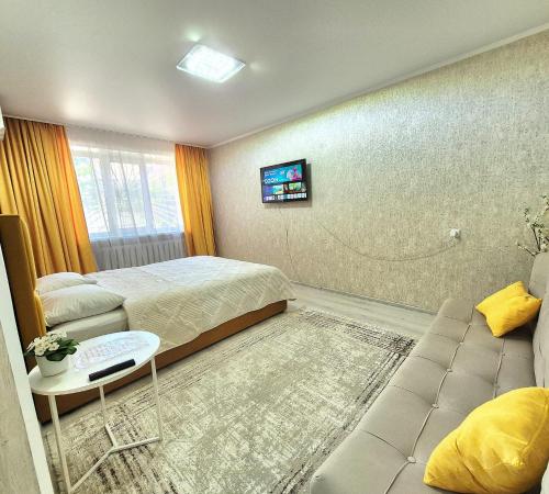 a hotel room with two beds and a couch at Однокомнатная на Хиуаз Доспановой 73 in Uralsk