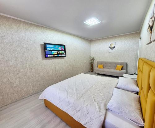 a bedroom with a bed and a tv on the wall at Однокомнатная на Хиуаз Доспановой 73 in Uralsk