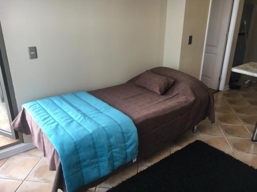 a small bed with a blue blanket on it in a room at EcoApart Concepción in Concepción