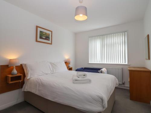 a bedroom with a white bed with two towels on it at Harcombe House Accessible Pet Free Bungalow Sleeps 6 in Newton Abbot