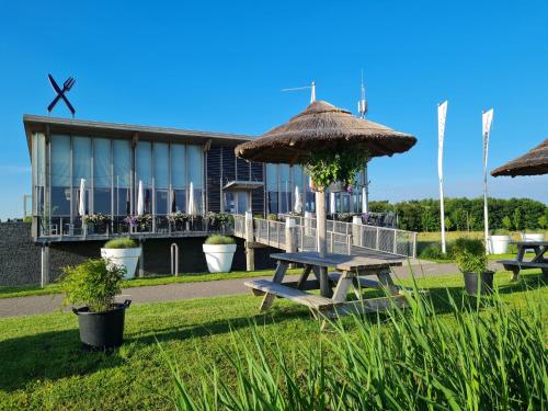 a picnic table and umbrellas in front of a building at Safari Lodges XL in Nieuwe Wetering