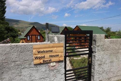 a gate with a sign on a wall with a house at Wood House Berat in Berat