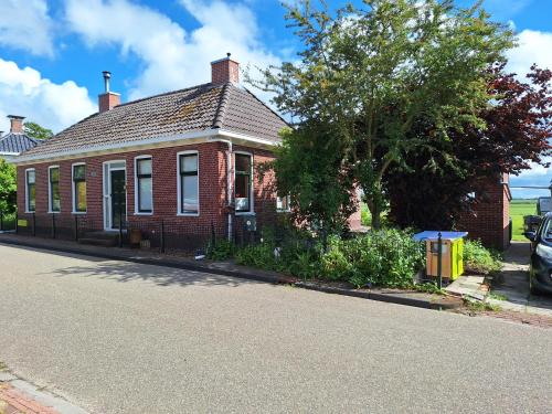 a red brick house on the side of a street at Kamer op de wierde Rottum in Rottum