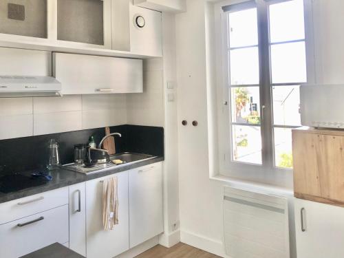 une cuisine blanche avec un évier et une fenêtre dans l'établissement le Pouliguen centre ville, au Pouliguen